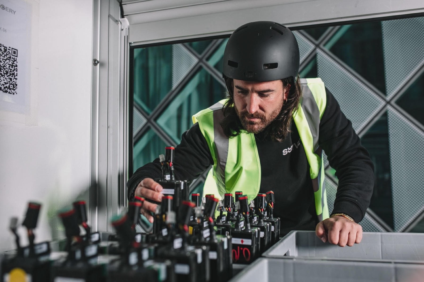 A man in a warehouse taking a battery out of a box full of batteries